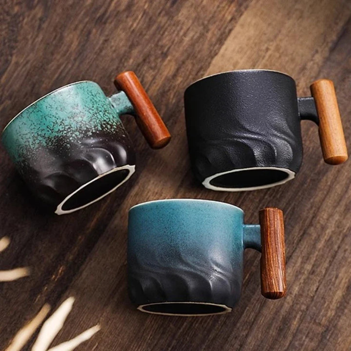 Three ceramic mugs with wooden handles on a wooden surface