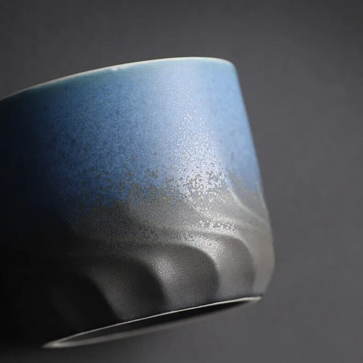 Blue ceramic cup with a textured surface on a dark background