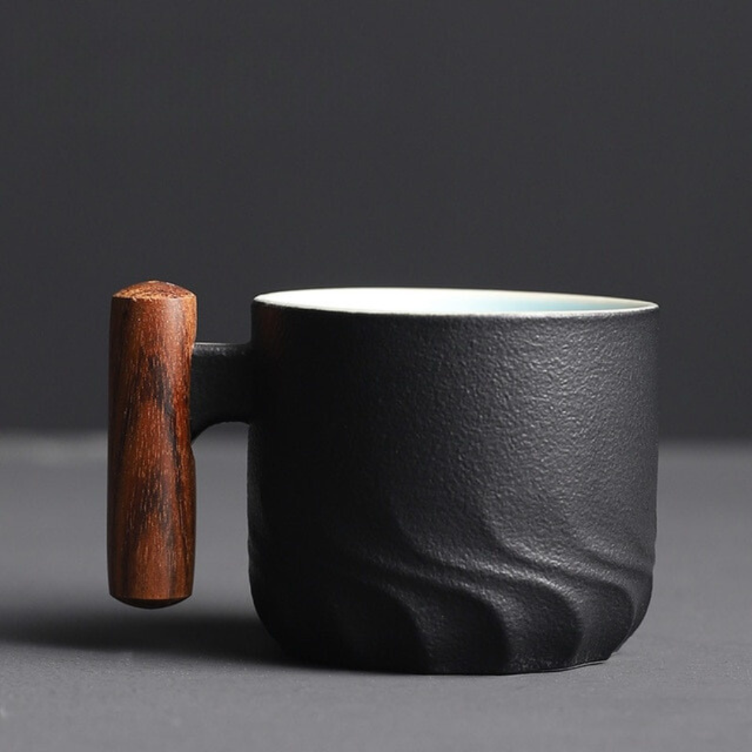 Black ceramic mug with a wooden handle on a dark background