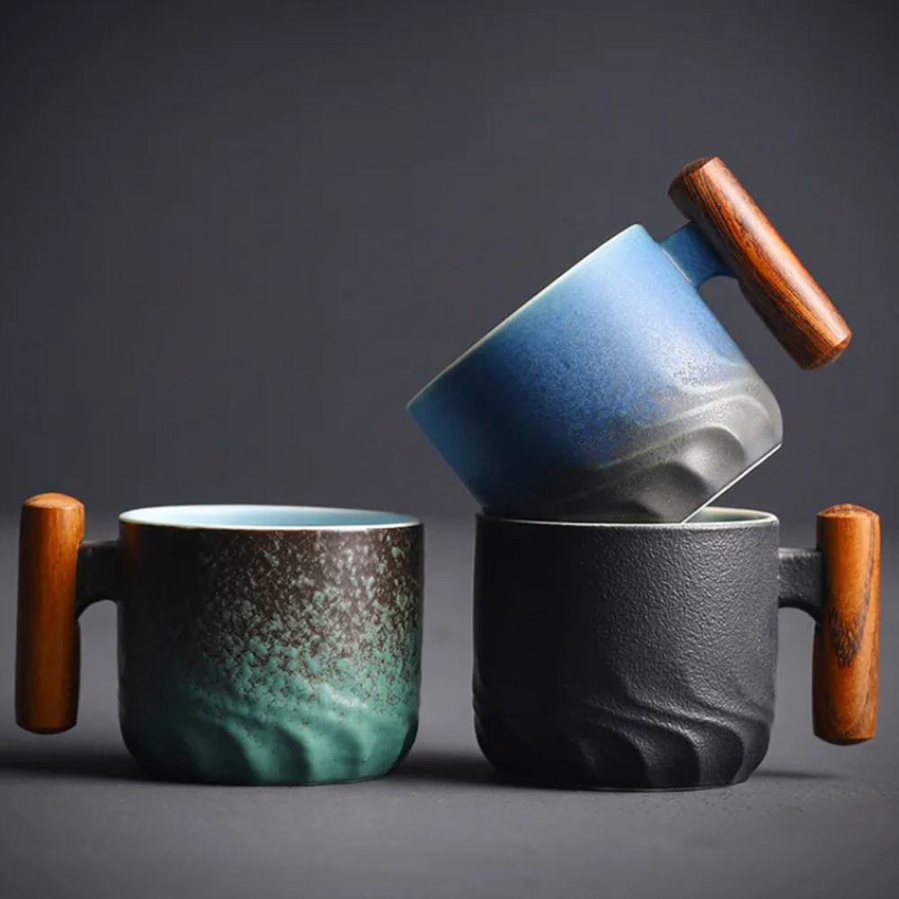 Three ceramic mugs with wooden handles on a dark background