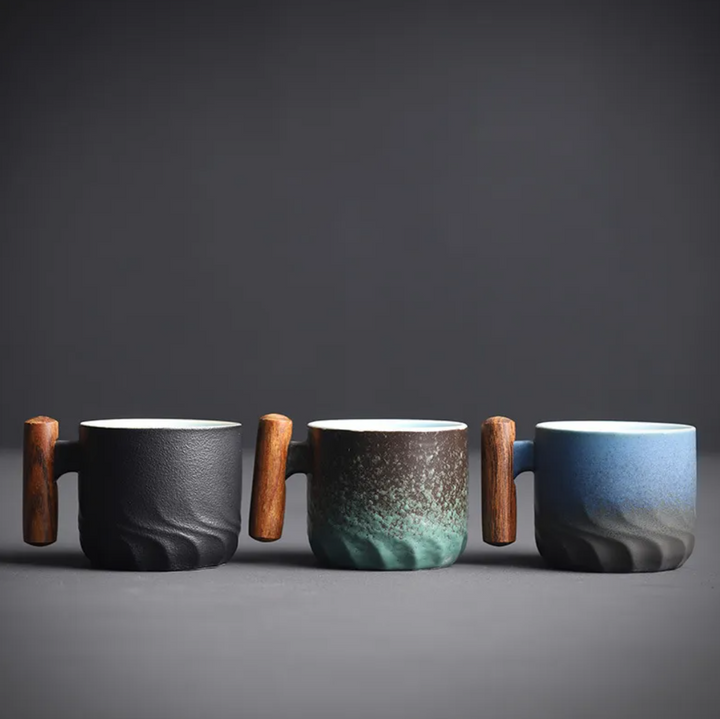 Three ceramic mugs with wooden handles on a dark background