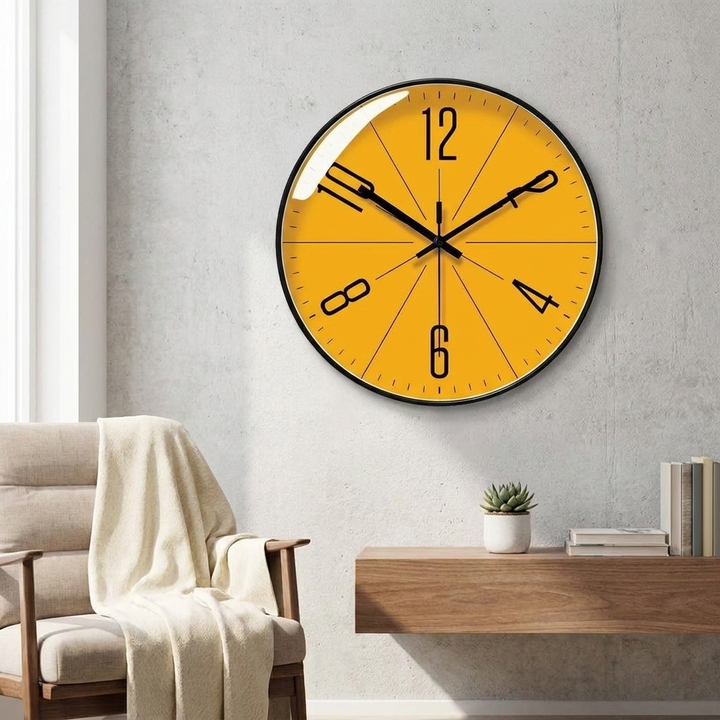 A round wall clock with a bright yellow face and black hands, mounted on a light gray textured wall above a wooden console table in a modern living room setting.