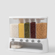 A white plastic 5-compartment grain dispenser with clear transparent bins filled with rice, millet, green beans, red beans, and soybeans, plus a small clear bowl at the bottom, shown on a light gray background.