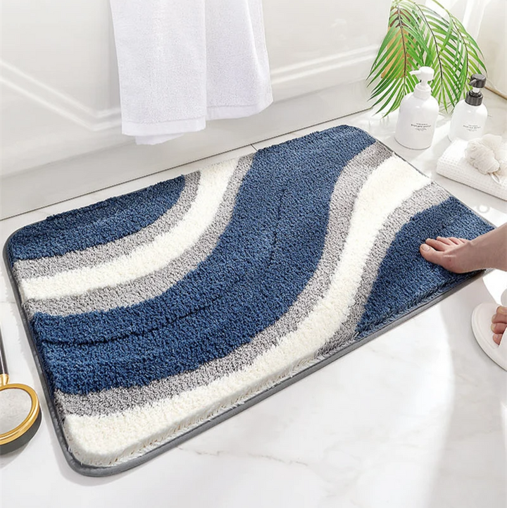 Bath mat with blue and gray wavy pattern on a bathroom floor.