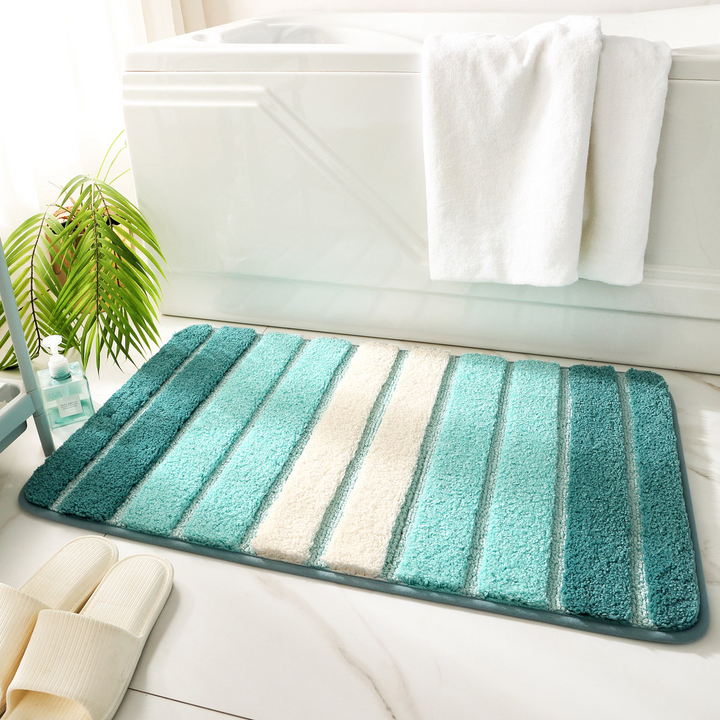 Striped bath mat with green and white colors on a bathroom floor.