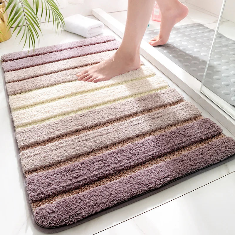 Gradient bath mat with horizontal stripes on a bathroom floor.