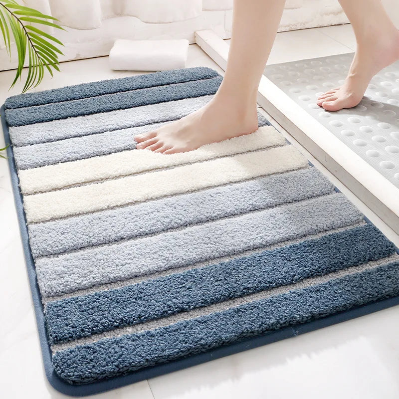 Striped bath mat with blue and gray gradient on a bathroom floor.