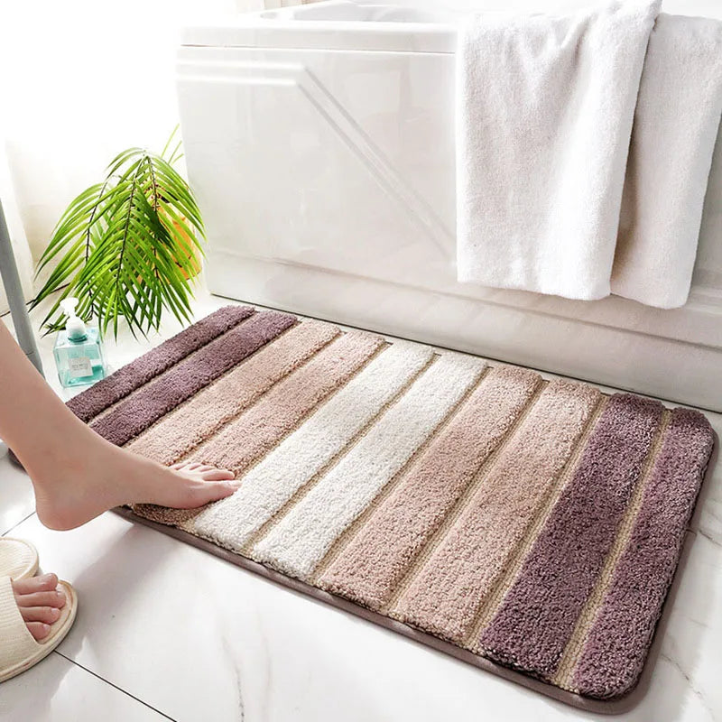 Striped bath mat with a foot stepping onto it, towel rack with white towels in the background.