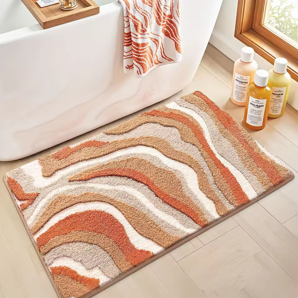 Bath mat with wavy pattern on a bathroom floor next to a bathtub and bottles.