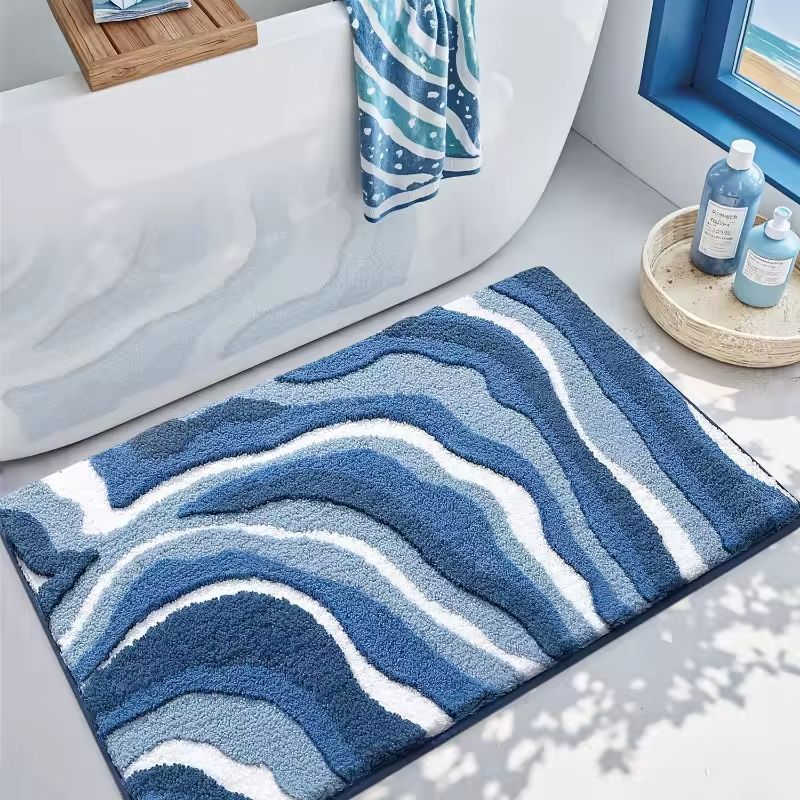 Blue and white wavy patterned bath mat in a bathroom setting with a bathtub and towels.