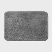 A rectangular gray bath mat with rounded corners and a plush, high-pile textured surface, shown against a light gray background.