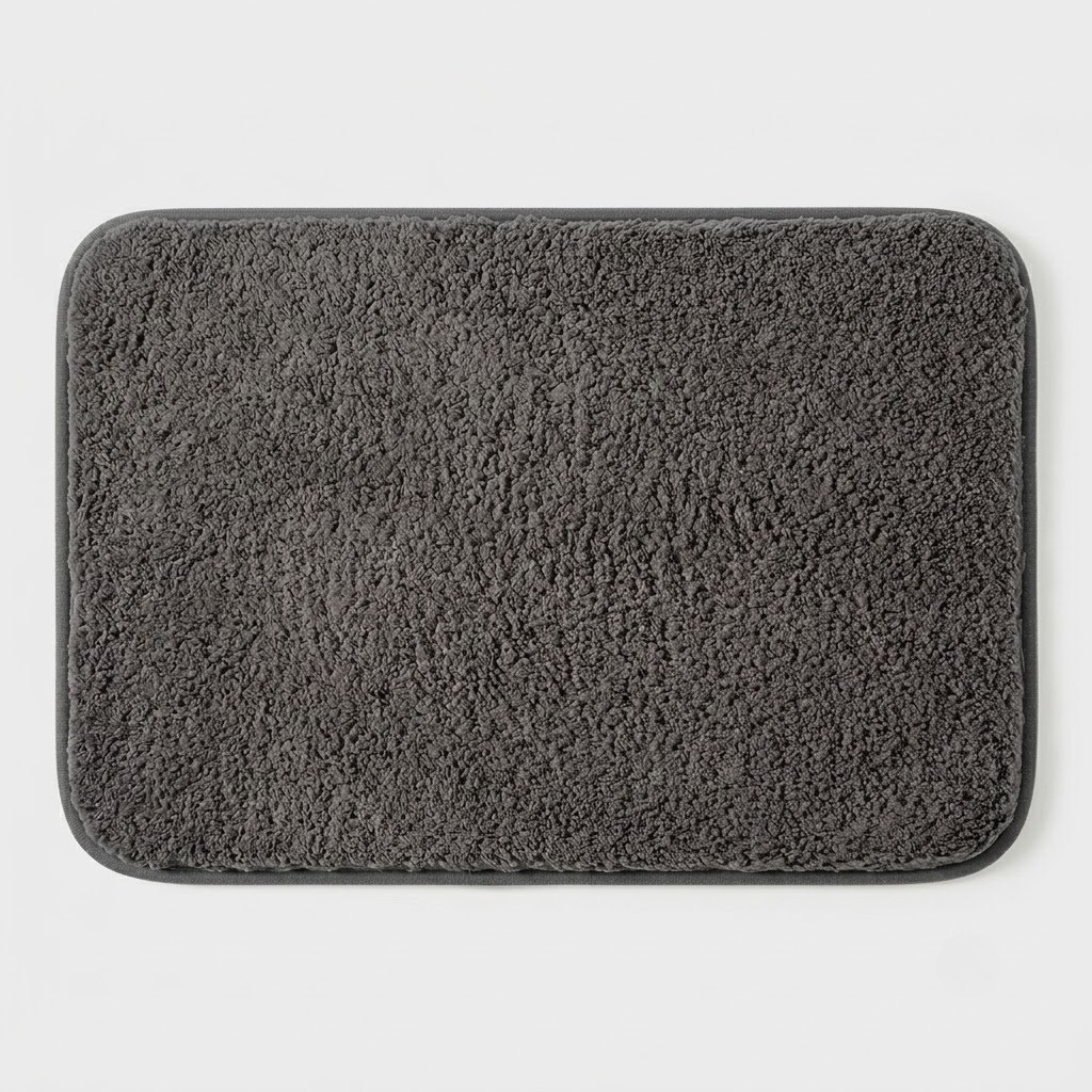A dark gray rectangular bath mat with rounded corners and a plush, textured surface, shown flat against a light gray background.