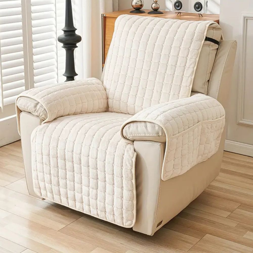Beige recliner chair with a quilted cover in a room with wooden flooring and white walls.