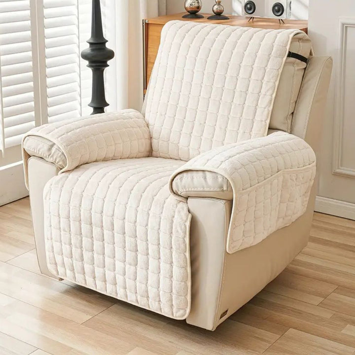 Beige recliner chair with a quilted cover in a room with wooden flooring and white walls.