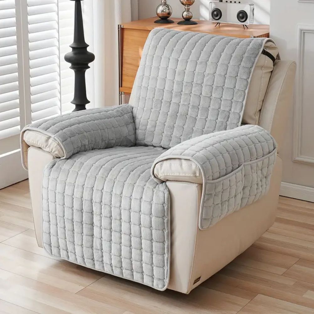 Gray quilted armchair cover on a beige armchair in a living room setting.