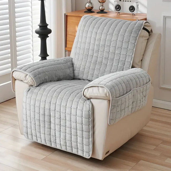 Gray quilted armchair cover on a beige armchair in a living room setting.