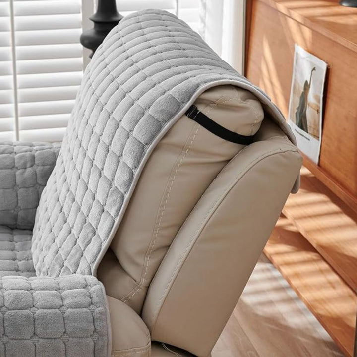 Gray quilted cover on a beige chair with a wooden cabinet in the background