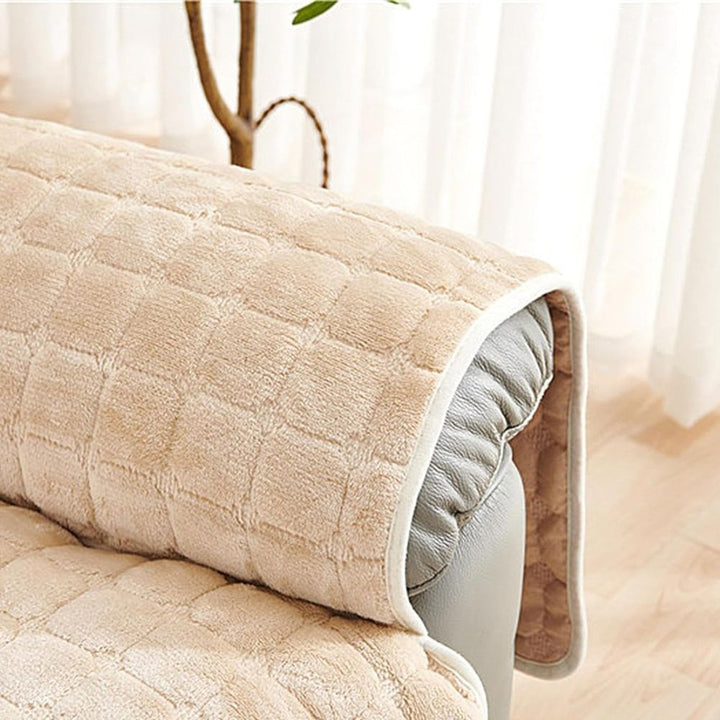 Beige quilted sofa cover on a white sofa with a light background