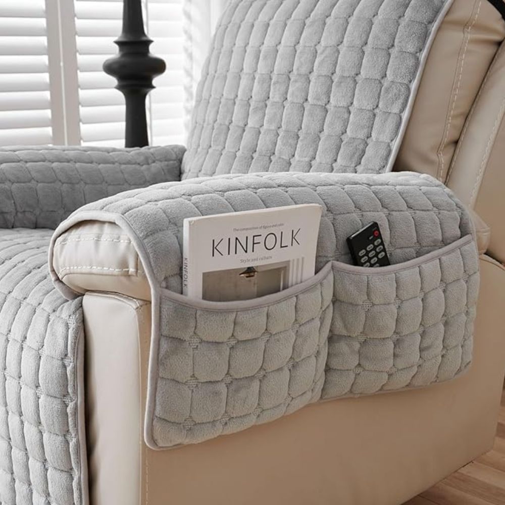 Gray quilted armrest cover on a beige armchair with a magazine and remote control inside.