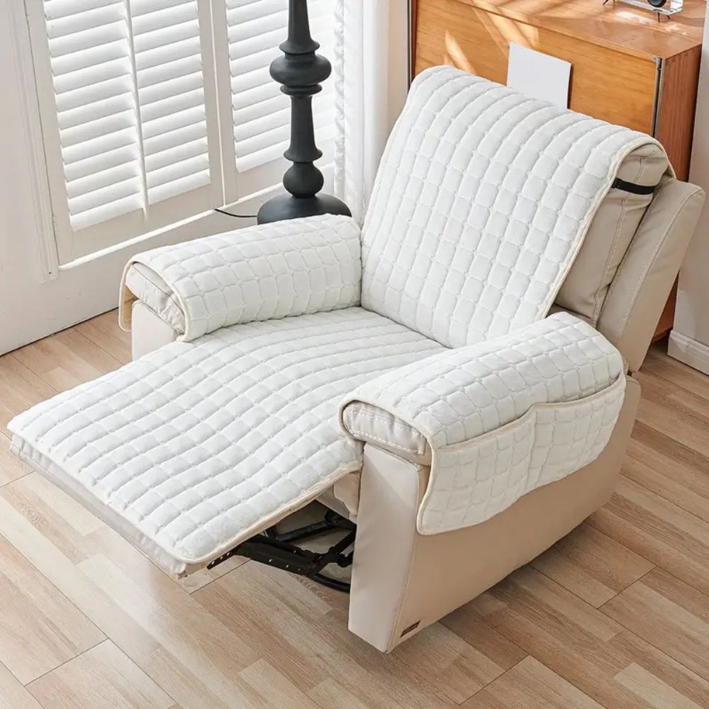 Beige recliner chair with quilted cover in a room with wooden floor and window.