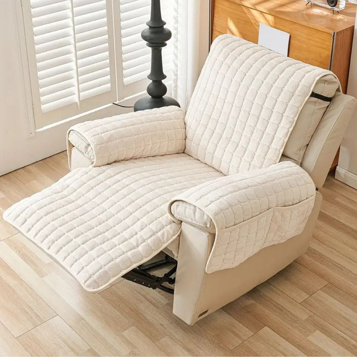 Beige recliner chair with quilted cover in a room with wooden floor and window.