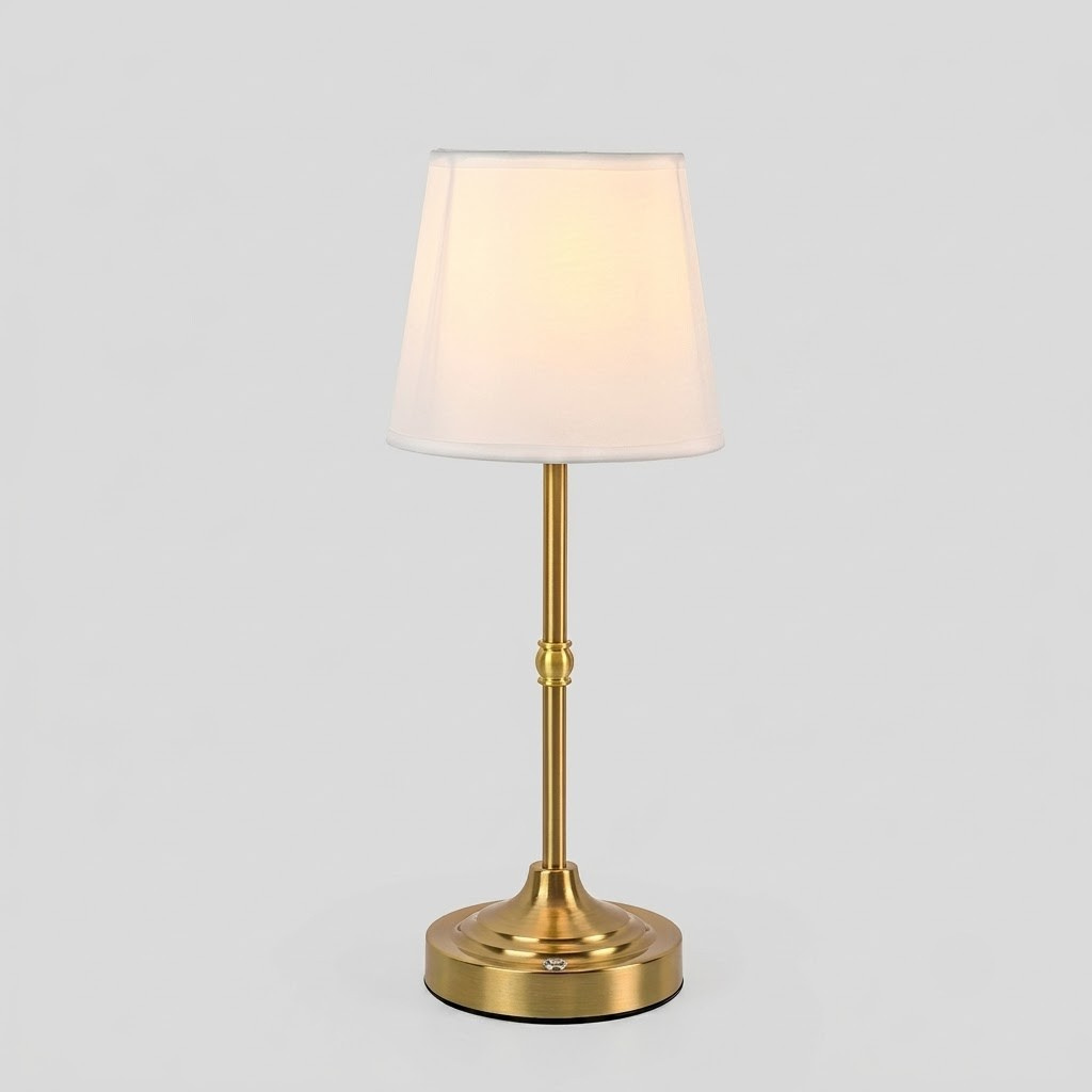 A modern table lamp with a tapered white fabric shade, a polished gold-finished metal stem, and a round gold base, shown illuminated against a neutral light gray background.