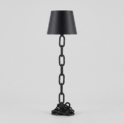 A black floor lamp with a tapered lampshade and a sculptural base made of interlocking chain links, photographed against a light gray studio background.