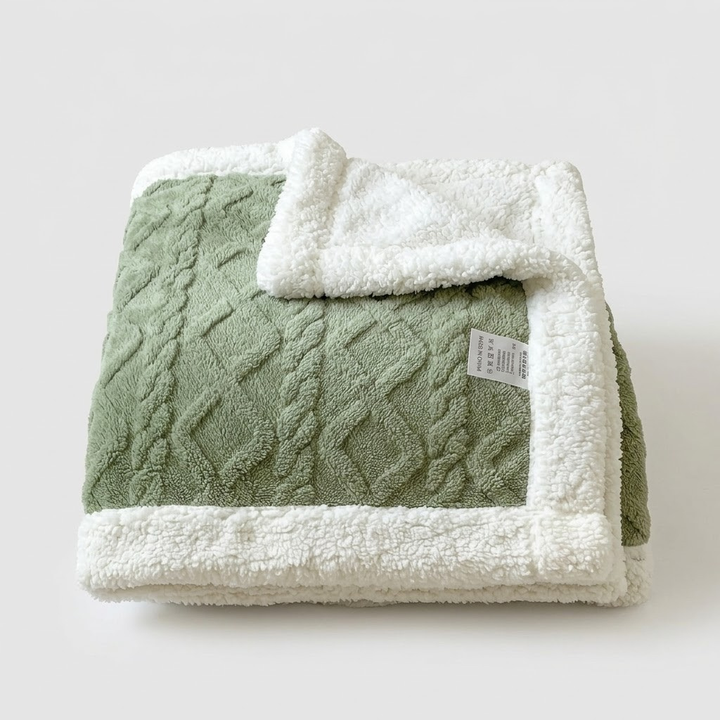 A folded knit blanket with a sage green textured cable-knit body and a plush white sherpa lining, shown on a light gray background.