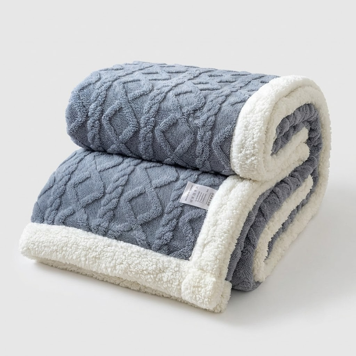 A folded throw blanket with a textured blue-gray cable knit top side and a plush cream sherpa fleece reverse, shown on a light gray background.