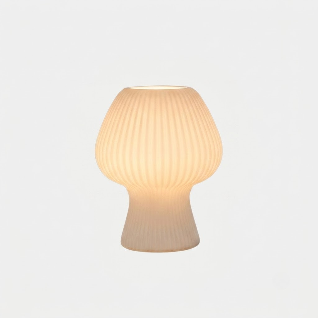 A small ribbed table lamp with a rounded mushroom-shaped shade and a flared base, glowing with a warm cream light against a plain white background.