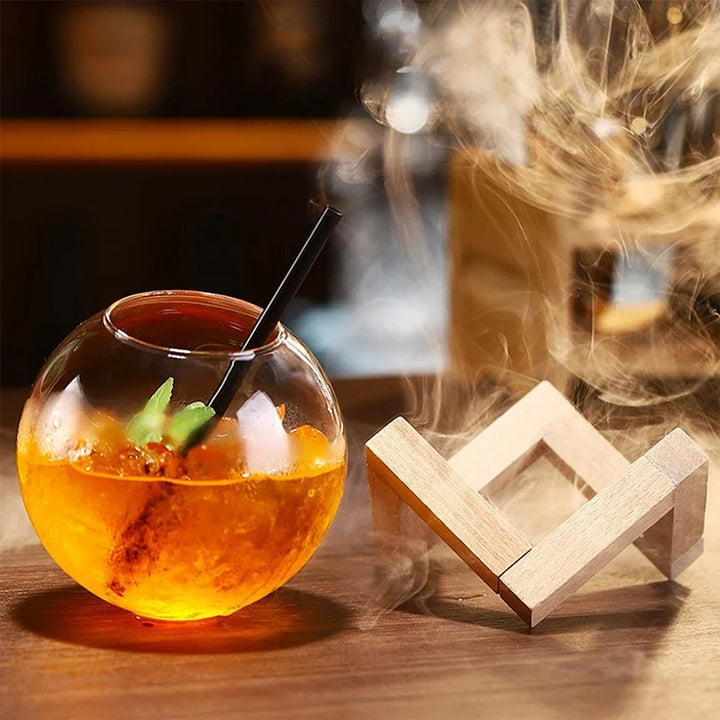 Glass bowl with an orange liquid and a wooden coaster on a wooden surface