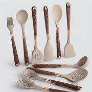 A 10-piece kitchen utensil set with beige silicone heads and dark brown wood-grain handles accented with rose gold metal collars, arranged on a light gray background.