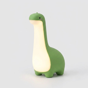 A dinosaur-shaped night light in green and cream, shown illuminated against a light gray background.