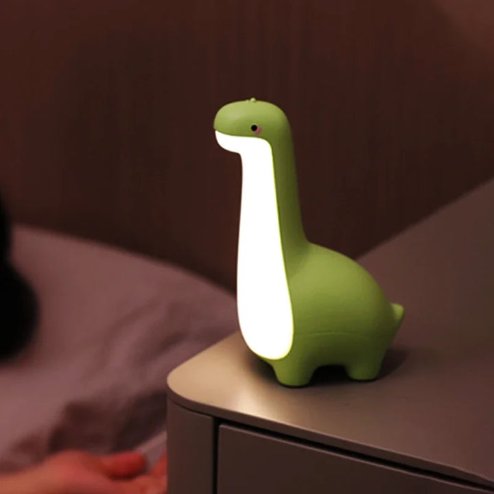 Green dinosaur-shaped night light on a surface with a blurred background