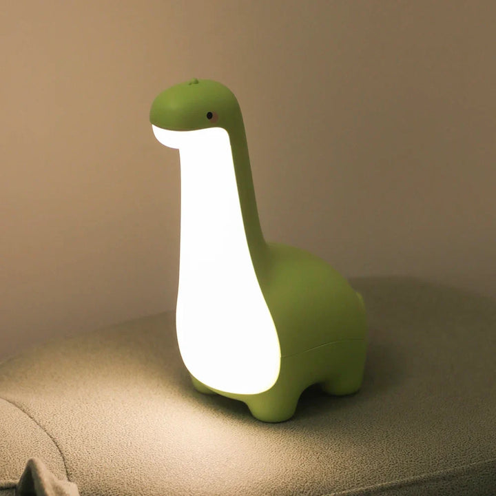 Green dinosaur-shaped night light on a surface with a beige background