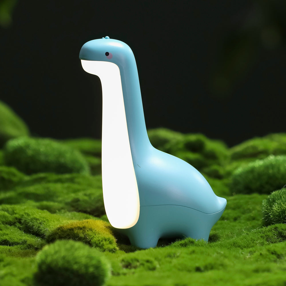 Blue dinosaur-shaped night light on a grassy surface with a dark background