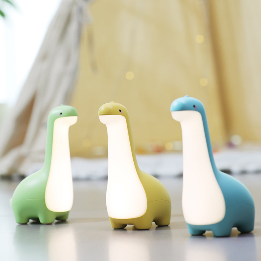 Three dinosaur-shaped lamps in green, yellow, and blue on a light surface with a blurred background.