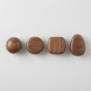 Four wooden cabinet knobs in different shapes—sphere, oval, rounded square, and teardrop—arranged in a row on a light gray background.