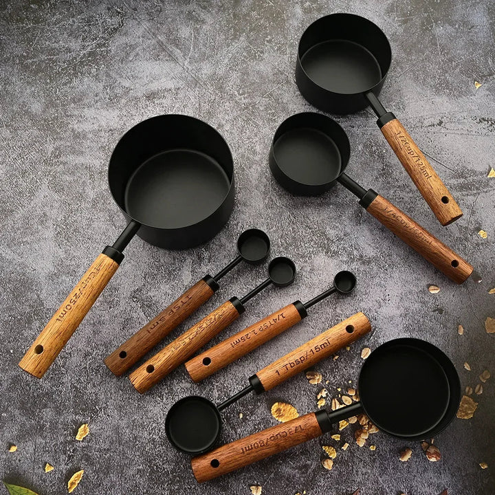 Set of black measuring cups with wooden handles on a gray surface