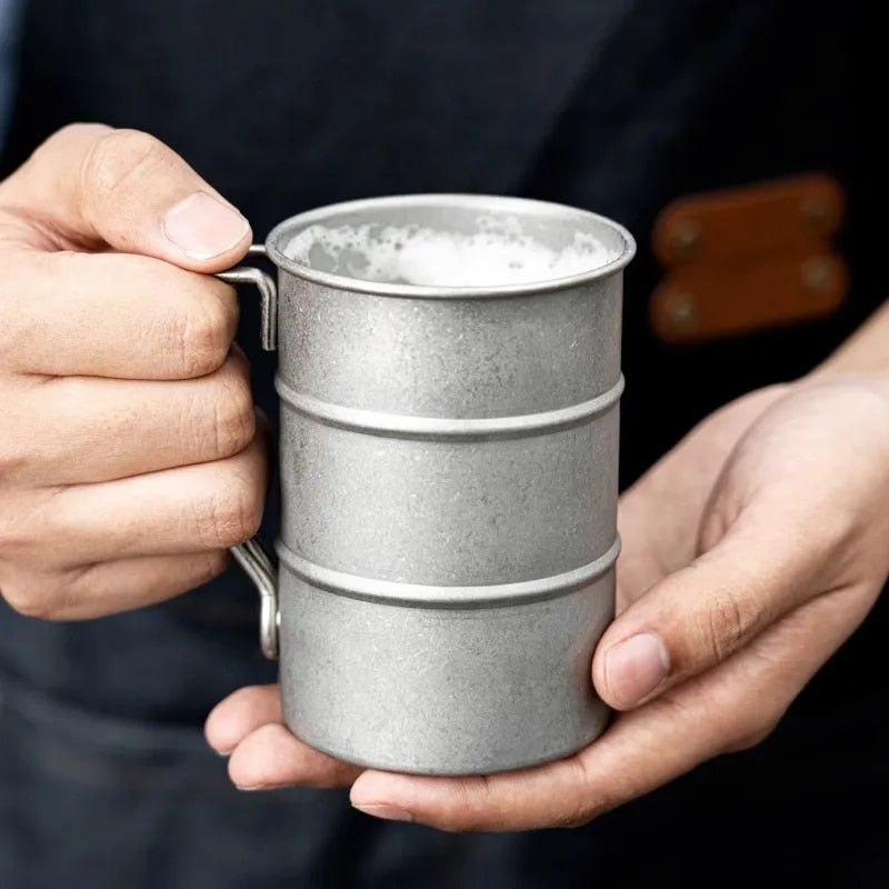 Person holding a textured metal mug with a dark background