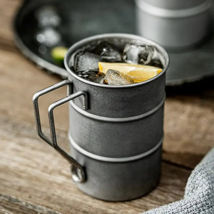 Gray metal cup with ice and lemon on a wooden surface