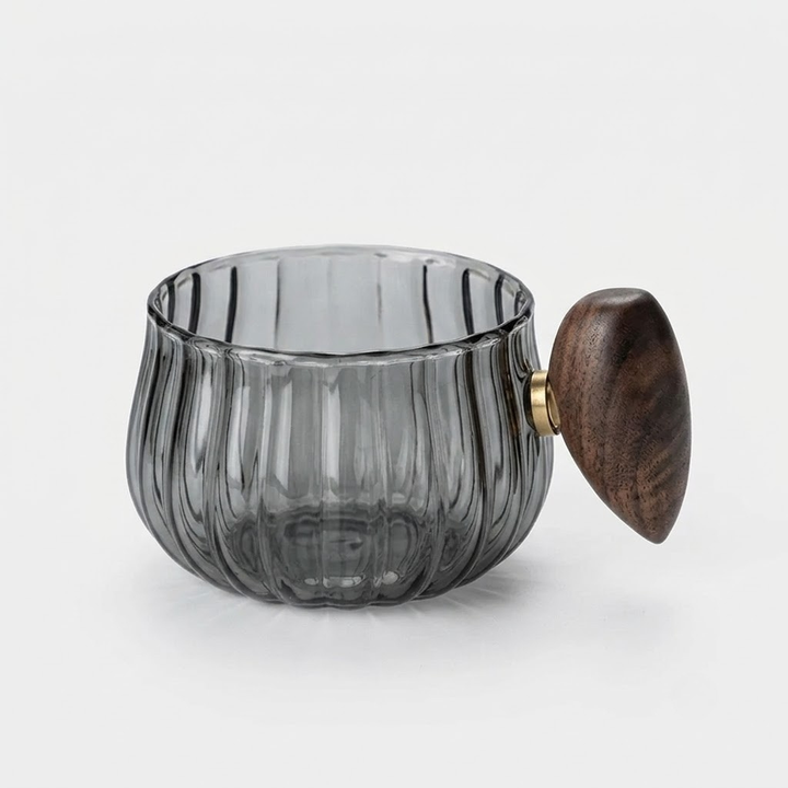 A ribbed translucent smoky gray glass cup with a dark brown wooden lid and a small gold metal accent ring, shown on a light gray background.