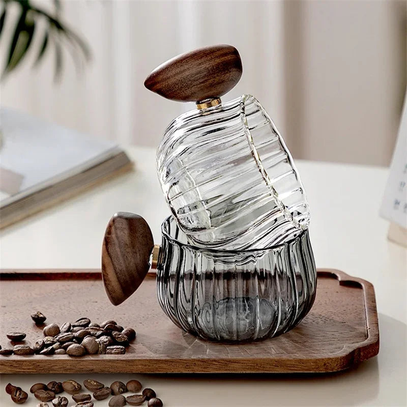 Glass container with wooden lids on a wooden tray with coffee beans