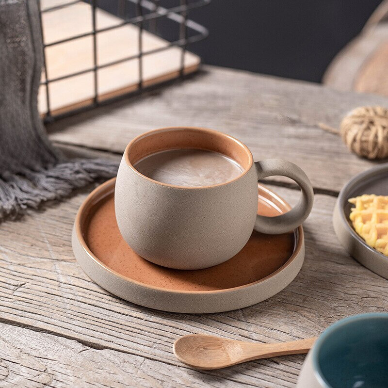 Ceramic cup with handle on a matching saucer on a wooden surface, with 'Flowerherd' branding.