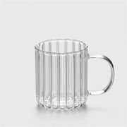 A clear ribbed glass mug with a flared rim and a curved handle, shown on a light gray background.