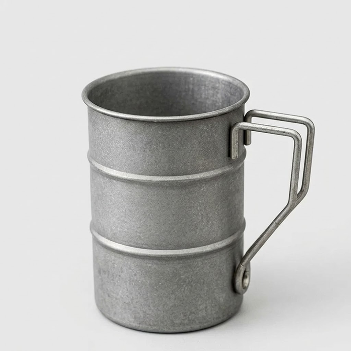 A galvanized metal camping mug with a fold-out handle, shown on a light gray background.